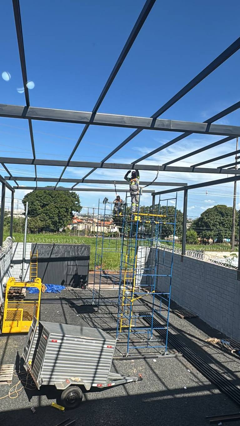 Andaime tubular montado para trabalho em estrutura de cobertura metálica, com trabalhador no alto